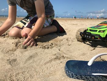 Low section of boy playing on sand at beach