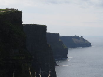 Scenic view of cliff by sea against sky