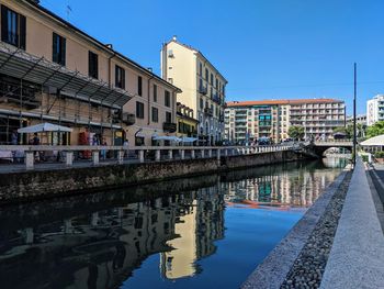 Bridge over canal by buildings against sky in city