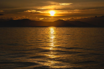 Scenic view of sea against dramatic sky during sunset