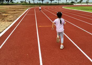 Rear view of female friends running on track