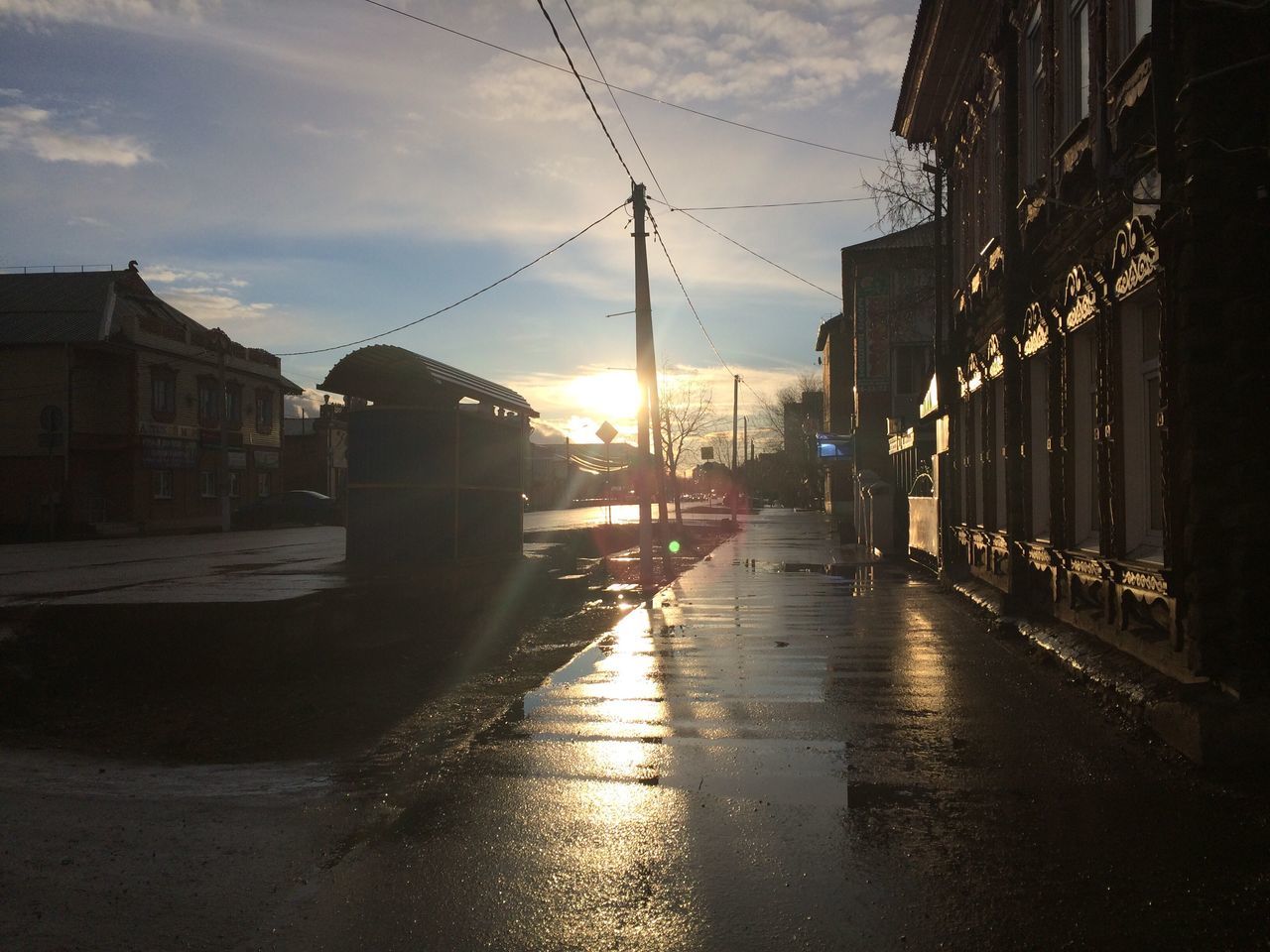 architecture, building exterior, built structure, the way forward, sky, sunset, city, street, diminishing perspective, transportation, vanishing point, sunlight, sun, road, building, street light, cloud - sky, cobblestone, residential building, residential structure