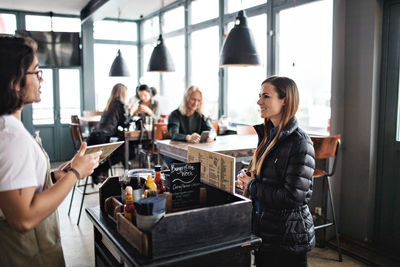 Owner talking to smiling young customer while standing in lectern