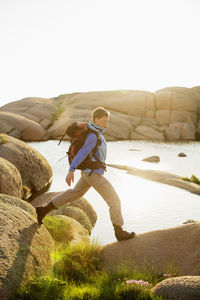 Side view of female backpacker hiking on rocks