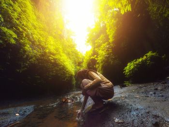 Rear view of man sitting on footpath in forest