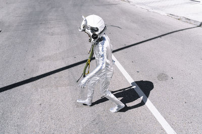 Boy in astronaut costume walking on road in city