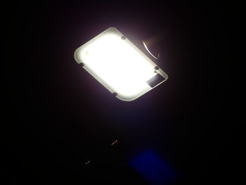 Low angle view of illuminated light bulb in darkroom