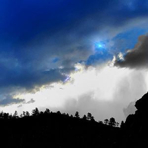 Low angle view of silhouette trees against blue sky