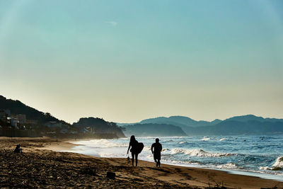 People on beach against clear sky