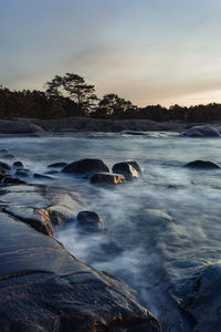 Scenic view of waterfall against sky during sunset