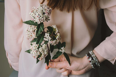 Midsection of woman holding flower behind back