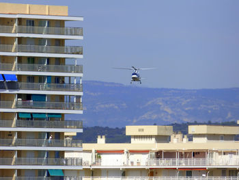Helicopter flying over buildings against clear sky