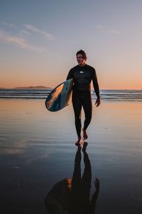 Full length of man standing on beach during sunset