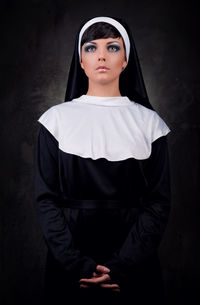 Nun standing against black background