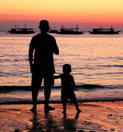 Silhouette men standing on beach against sky during sunset