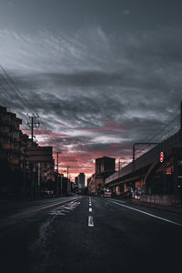 Road by city against dramatic sky