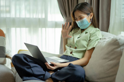 Young woman wearing mask talking on video call at home