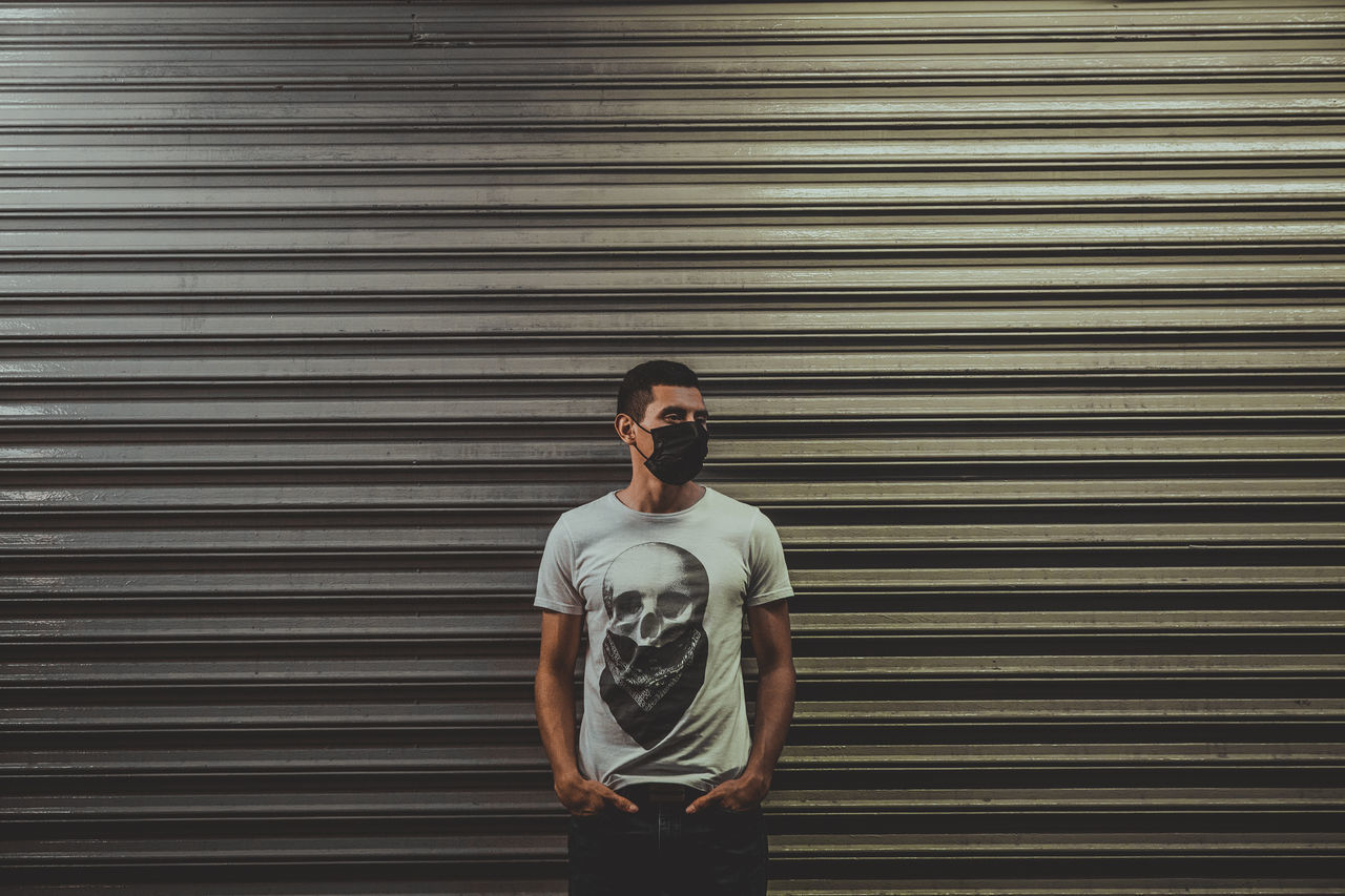 FULL LENGTH OF YOUNG MAN STANDING AGAINST WALL