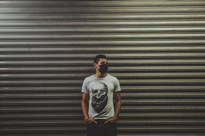 Portrait of young man standing against wall