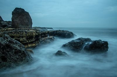 Scenic view of rocks in sea against sky