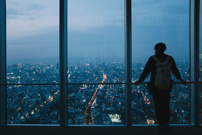 Man standing by window in city