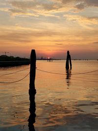 Silhouette people on beach against sky during sunset