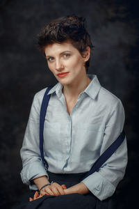 Portrait of smiling woman sitting against wall