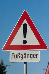 Close-up of road sign against blue sky