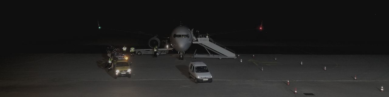 transportation, air vehicle, mode of transportation, airplane, airport, night, airport runway, illuminated, no people, stationary, travel, land vehicle, public transportation, road, aerospace industry, outdoors, motor vehicle, military, runway, on the move