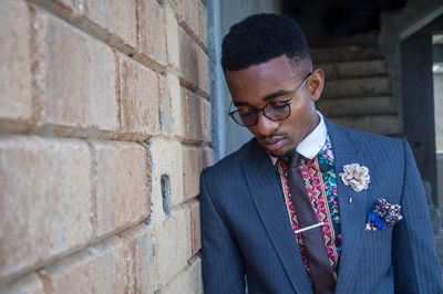 Young man in suit standing against wall