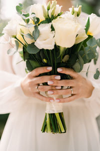 Midsection of bride holding bouquet