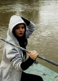 Young woman holding metal against lake