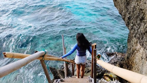 High angle view of woman standing on steps by sea