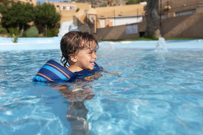 Toddler plays in the pool with children's floats. summer arrives in the northern hemisphere.