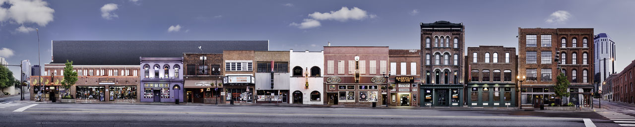 Buildings by road against sky in city