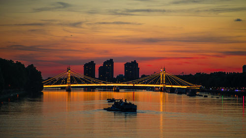 Silhouette bridge over river against sky during sunset