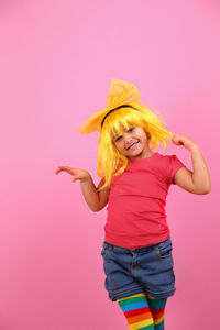 Portrait of smiling girl standing against pink background