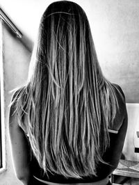 Rear view of woman sitting against wall at home