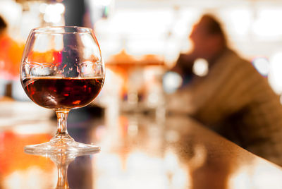 Reflection of man drinking glass on table