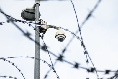 Low angle view of security camera against sky