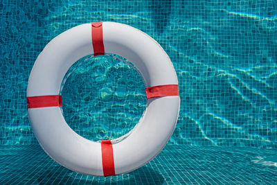 Top view of lifebuoy floating on top of sunny blue water in the swimming pool