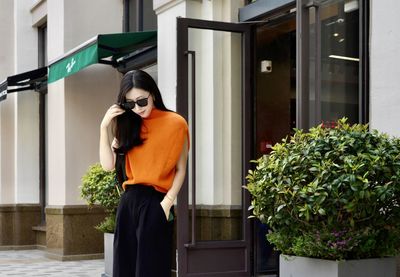 Portrait of young woman standing against building