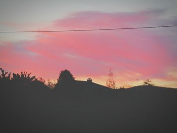 Low angle view of silhouette houses against scenic sky