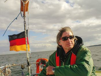 Man wearing sunglasses in boat on sea against sky