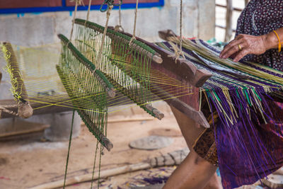 Midsection of woman weaving on handloom