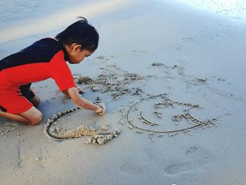 Side view of boy playing with sand at beach