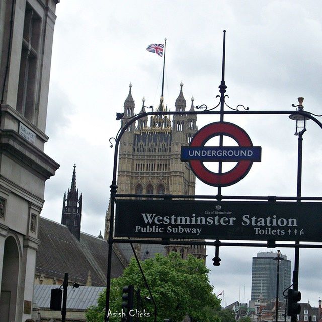 building exterior, architecture, text, communication, built structure, western script, road sign, city, low angle view, guidance, information sign, sky, sign, information, arrow symbol, road signal, non-western script, directional sign, street light, flag