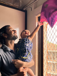 Side view of little baby girl looking away with her father and feeling happy.