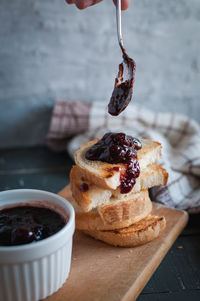 Close-up of toasted slices of bread with homemade strawberry jam dripping from spoon