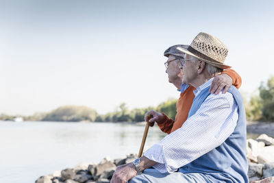 Two old friends sitting on a tree trunk, watching the river